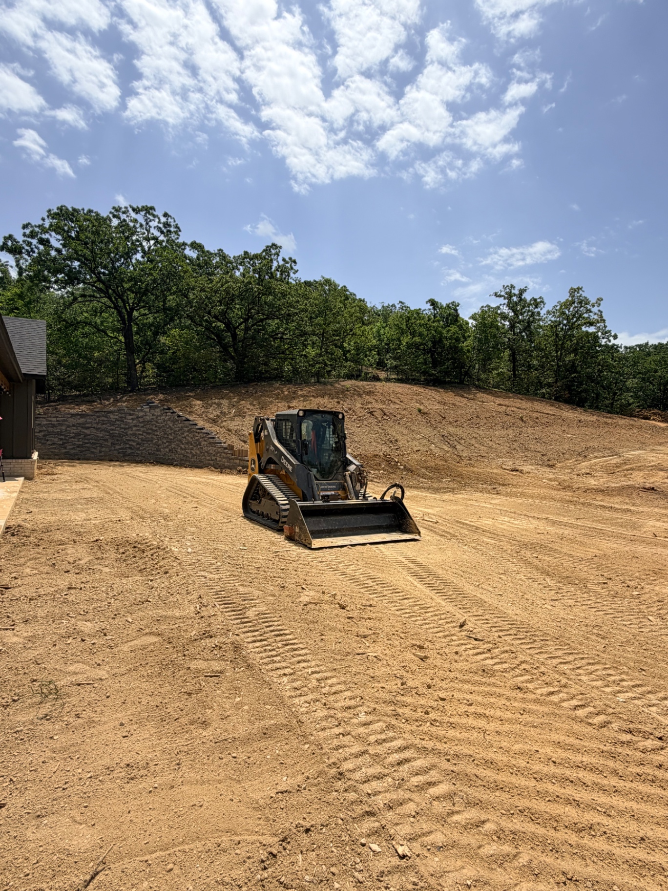 John Deere skid steer and Bobcat track loader grading a freshly cleared jobsite